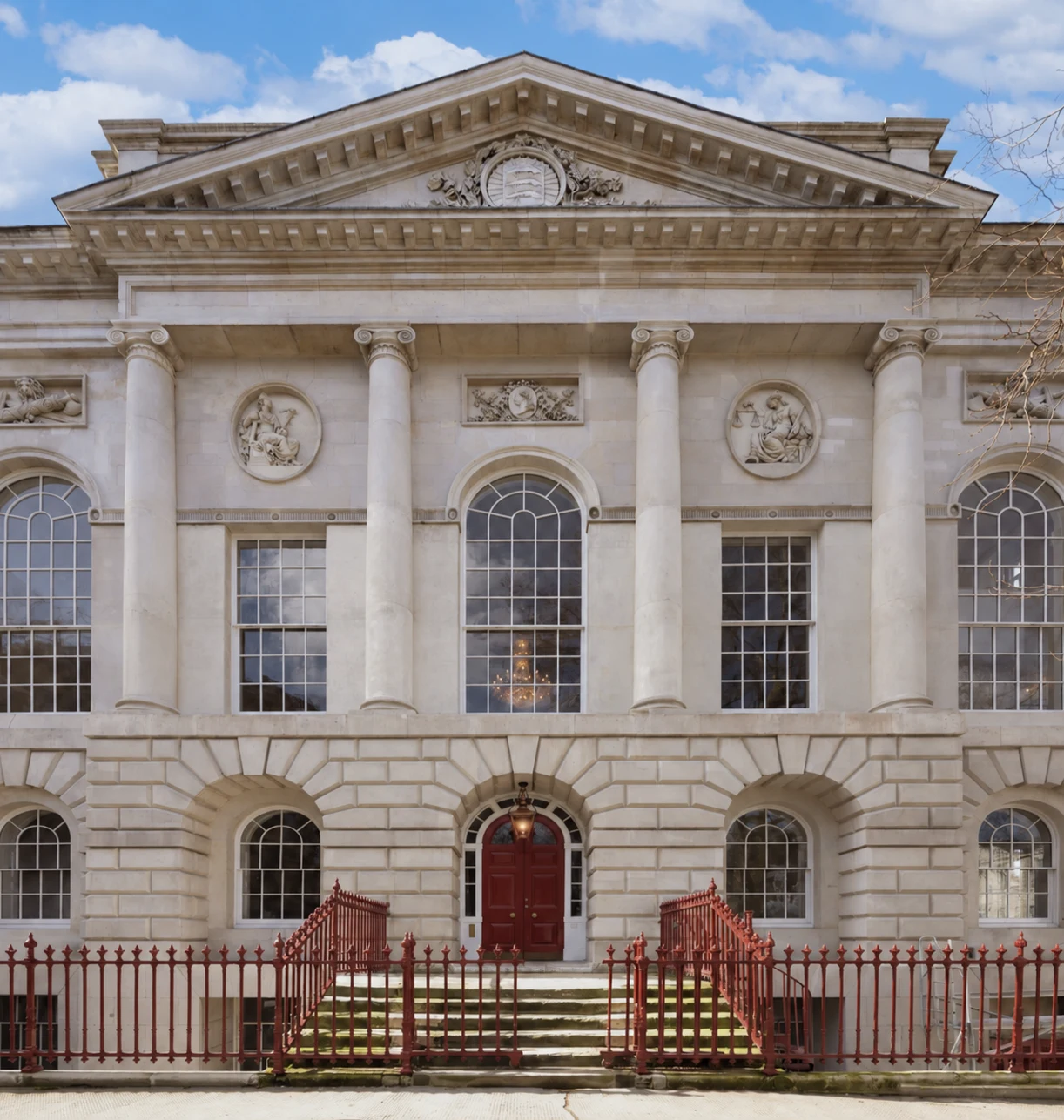 Stone venue facade with tall columns, arched windows, and a red entrance gate