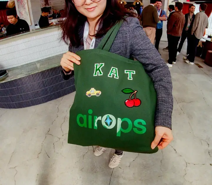 Attendee showing a personalized green AirOps tote bag